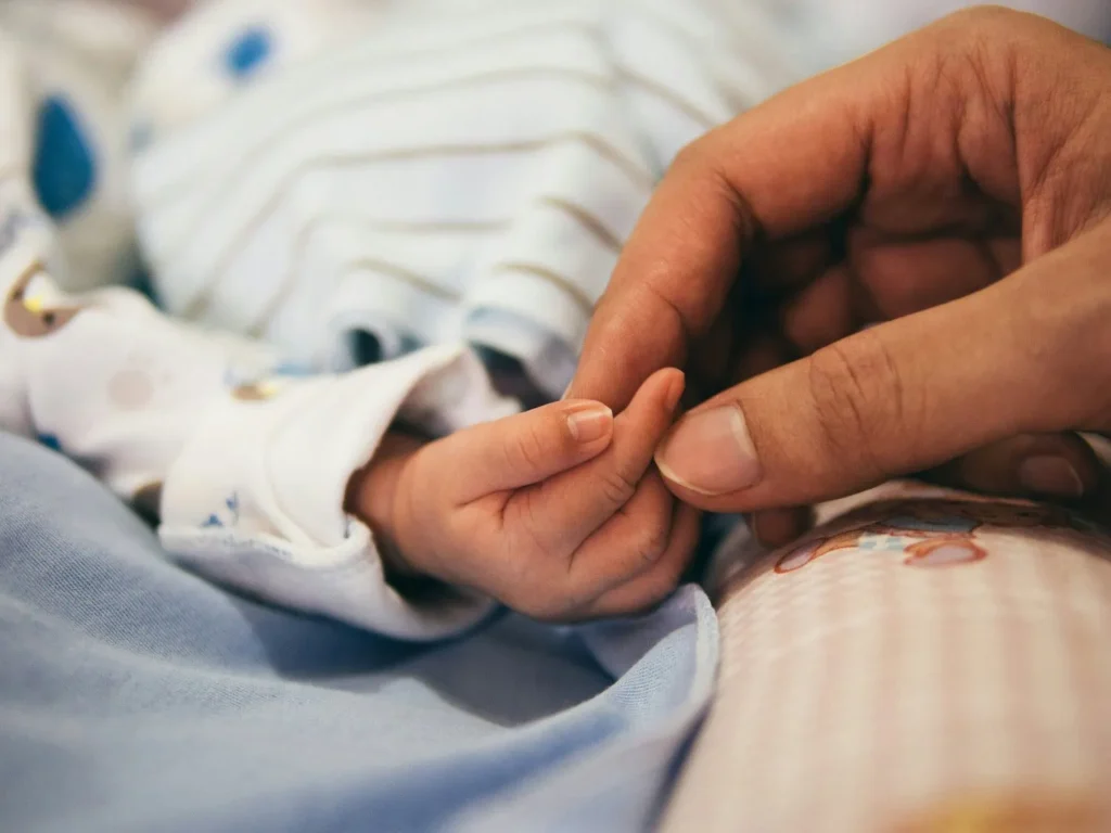 mother holding baby hand during postpartum doula services